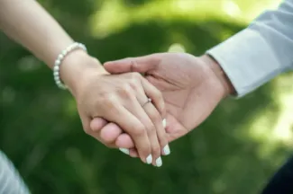 a man and woman holding hands in the grass
